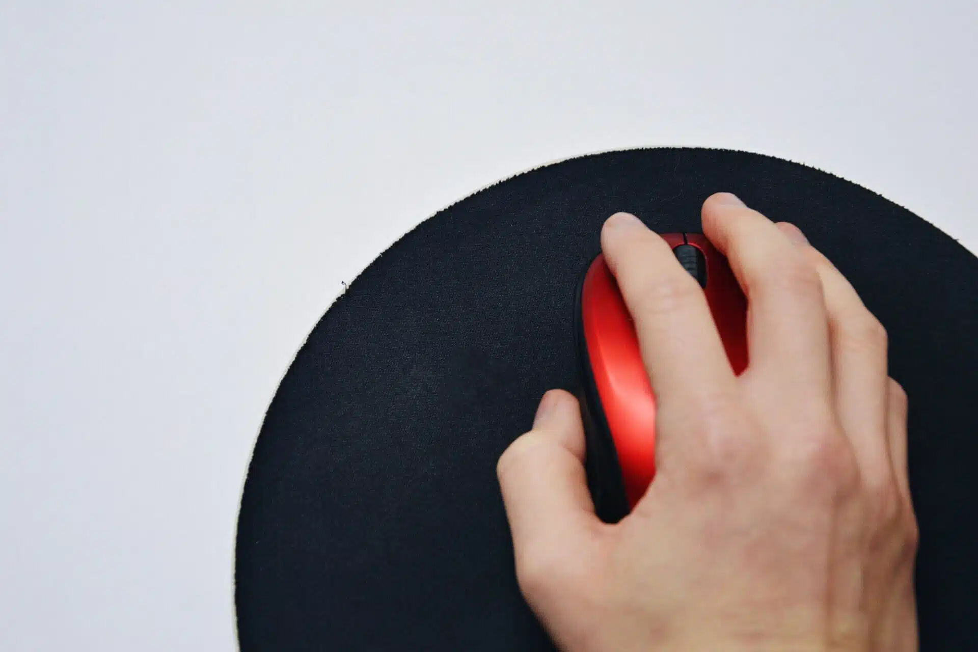 Overhead photo of a hand holding a red wireless computer mouse