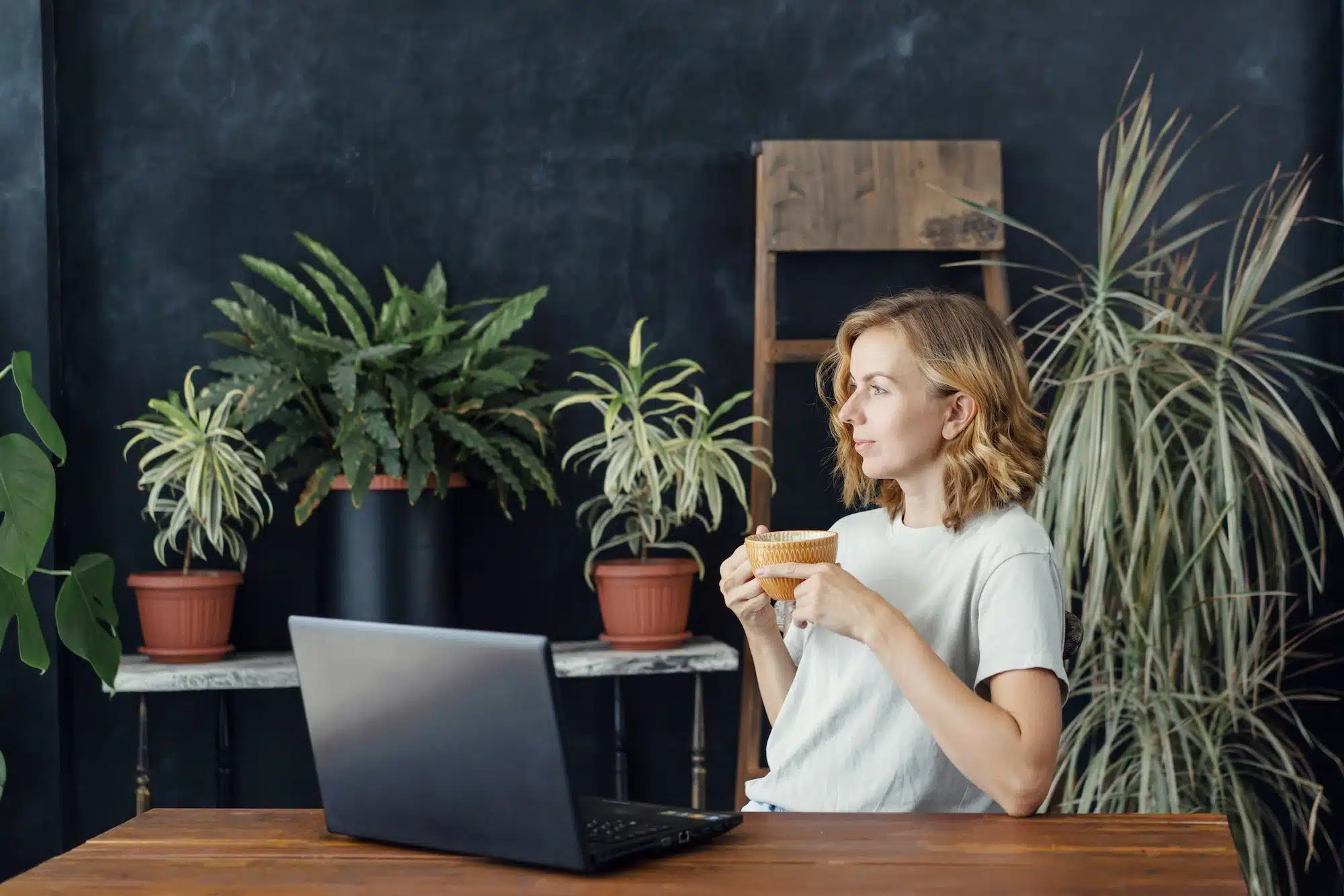 woman in stylish office with many tropical plants in pots