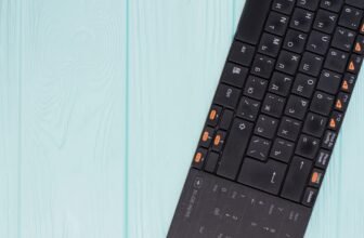 Black computer keyboard on light blue background.