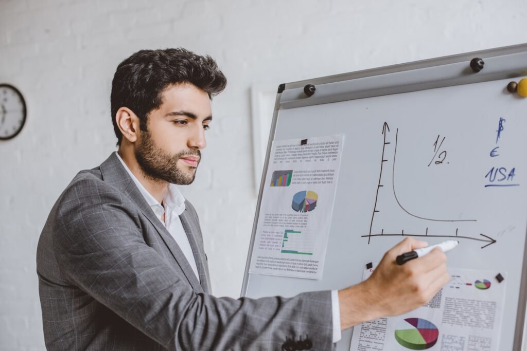 handsome businessman drawing chart on flipchart with marker pen in office