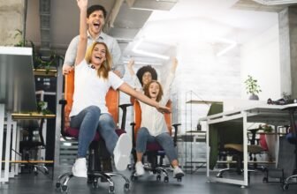 Overjoyed millennial colleagues racing on office chairs