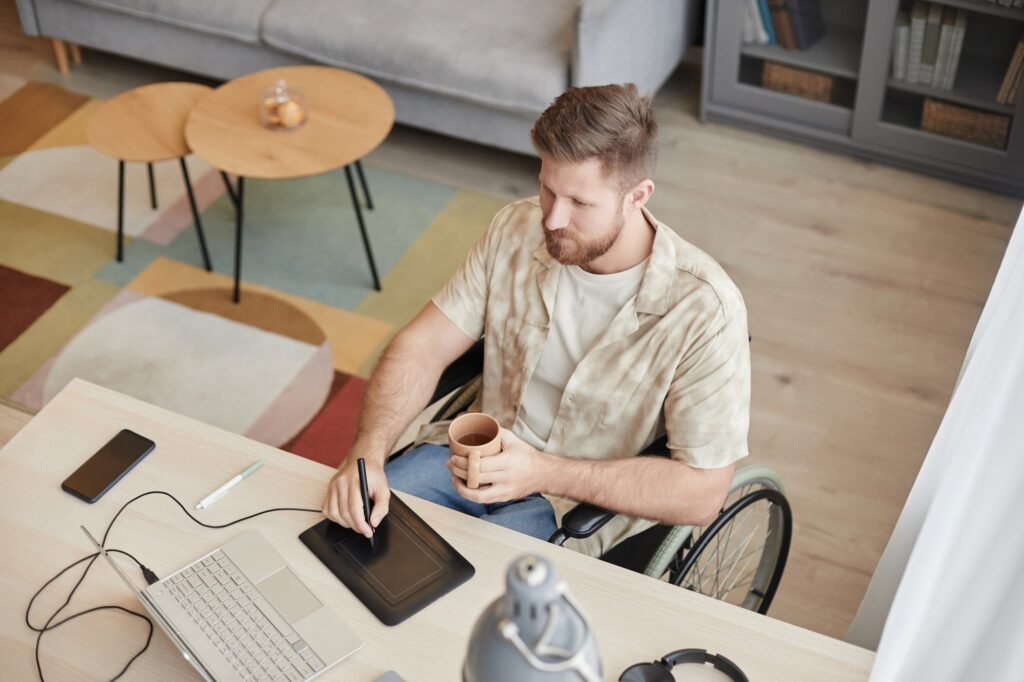 Top View at Man with Disability Working at Home Office with Pen Tablet