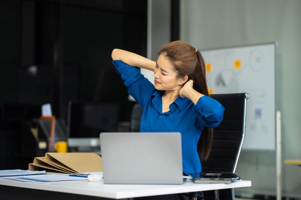Businesswoman stretches to ease office syndrome from prolonged sitting.