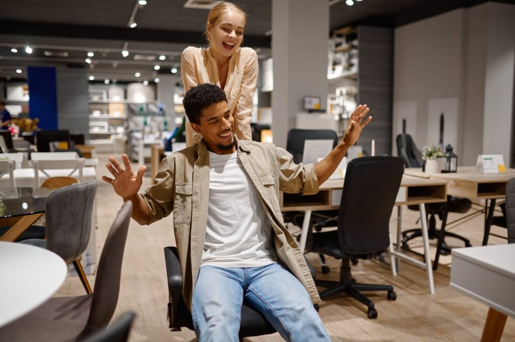 Funny couple riding office chair at shop