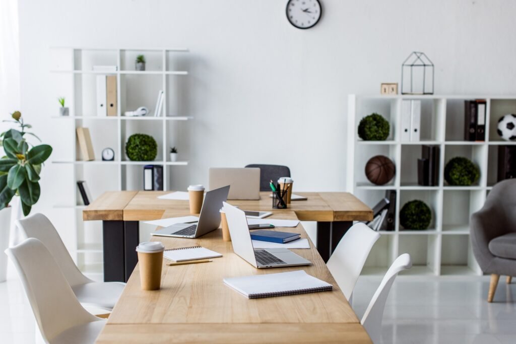 interior of modern business office with laptops on table, chairs and furniture