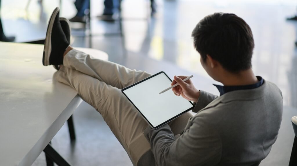 Young businessman using a tablet. He sat on a chair and his feet rested on the table.