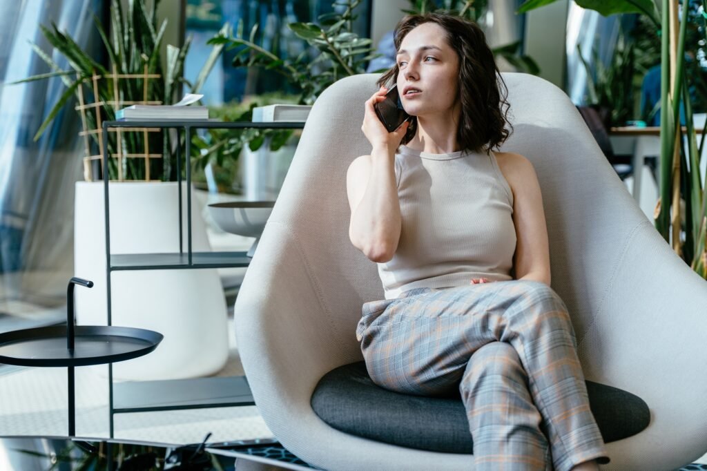 Young woman in smart casual talking on phone in office lounge